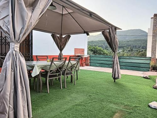 una mesa con sillas y una sombrilla en el césped en La casita de la Alquería, Montanejos, en Montanejos