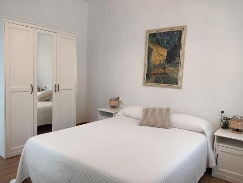 a white bedroom with a bed and a painting on the wall at La casita de la Alquería, Montanejos in Montanejos