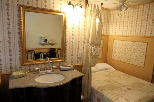 a bathroom with a sink and a bed and a mirror at Auberge des Cévennes in LʼAnse-Saint-Jean