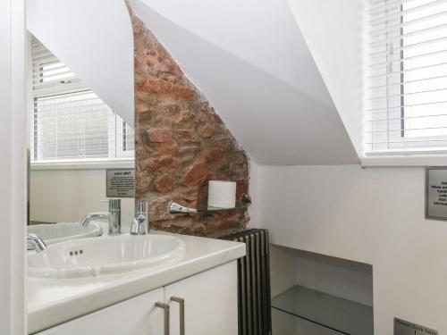 baño con lavabo y pared de piedra en Pebble Bay en Brixham