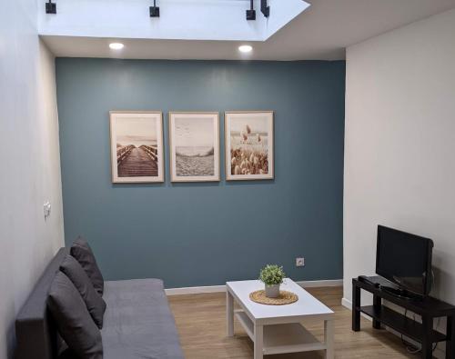ein Wohnzimmer mit einer blauen Wand mit Bildern darauf in der Unterkunft Appartement 10A - RDC-centre ville-local vélo in Malestroit