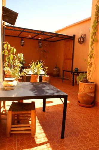 a patio with a table and a bunch of potted plants at Maison d'hôtes Dar El Nath in Ouarzazate