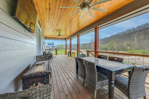 a porch with a table and chairs and a ceiling fan at Riverfront Caddo Shack Home with Views and Fire Pit in Glenwood