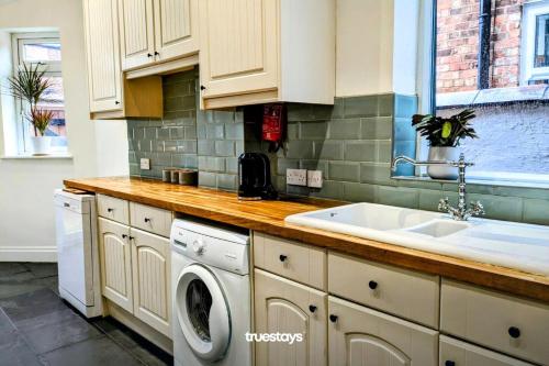 uma cozinha com um lavatório e uma máquina de lavar roupa em Crawford House - Stunning 2 Bedroom House in Manchester em Manchester
