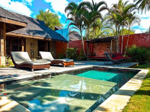 a swimming pool with two chairs and a house at Villa Mitirapa in Tohautu