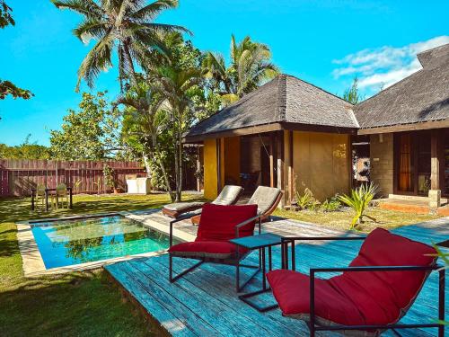 a patio with red chairs next to a pool at Villa Mitirapa in Tohautu