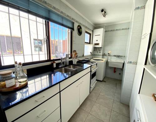 cocina blanca con fregadero y ventana en Lindo Departamento en Buenos Aires
