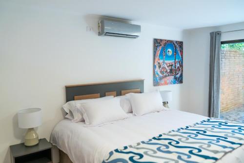 1 dormitorio con 1 cama grande con sábanas blancas y ventana en Park Güell House Hotel, en Talca