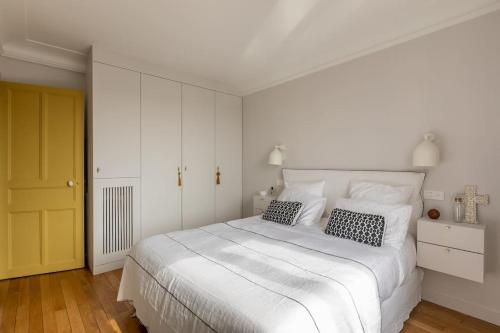 - une chambre blanche avec un grand lit blanc et 2 oreillers dans l'établissement Le PAVILLON SUPERBE APPARTEMENT PROCHE ROLLAND GARROS &PRINCES, à Boulogne-Billancourt