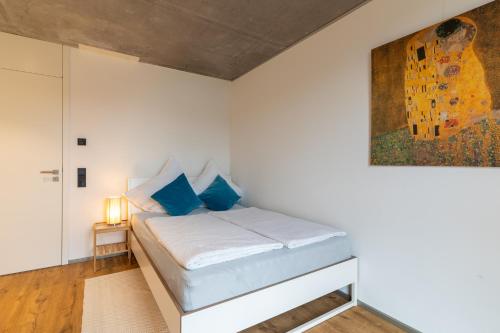 ein Schlafzimmer mit einem Bett mit blauen Kissen und einem Gemälde in der Unterkunft ViCas Ferienwohnung in Kappel-Grafenhausen