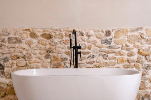 a white bath tub in front of a stone wall at DODO etc in Nyons