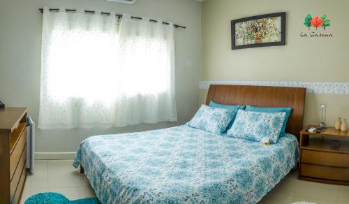 1 dormitorio con 1 cama con edredón azul y ventana en Pousada La Casona, en Tibagi