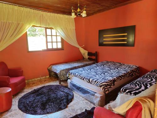 een kamer met 2 bedden, een stoel en een raam bij Sítio da Fabi in Brumadinho