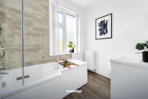 baño blanco con bañera y ventana en NEW Stanley House - Stunning 2 Bedroom House en Etruria