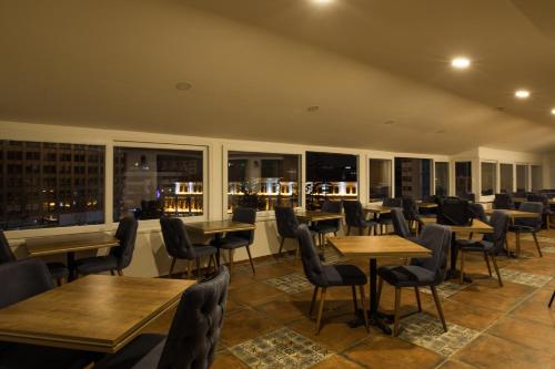 un ristorante con tavoli e sedie in legno e finestre di Manzara Hotel a Eskişehir