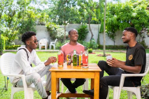 un gruppo di tre uomini seduti intorno a un tavolo con bevande di Moments Lodge a Lilongwe