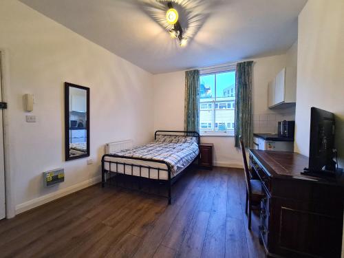 a bedroom with a bed and a tv in a room at The Greenwich Pensioner Guesthouse in London