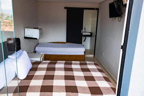 Cette petite chambre comprend un lit et une télévision. dans l'établissement Pousada Caraguatatuba Praia Indaia Quarto 02, à Caraguatatuba