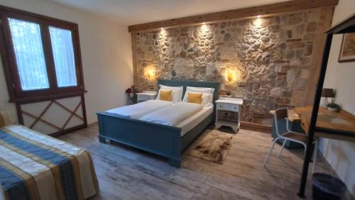 1 dormitorio con cama y pared de piedra en Le Zampolle B & B, en Colà di Lazise