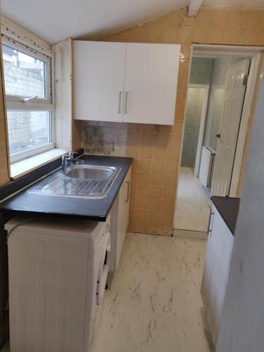 uma pequena cozinha com um lavatório e uma janela em AR Homes em Middlesbrough