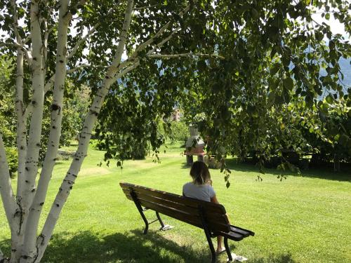 a woman sitting on a bench in a park at Affittacamere Verger Plein Soleil in Saint-Pierre