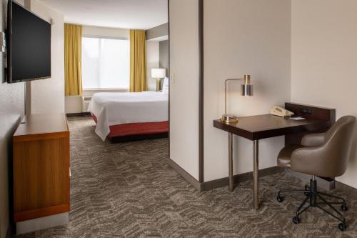 a hotel room with a bed and a desk and a television at SpringHill Suites Portland Airport in Portland