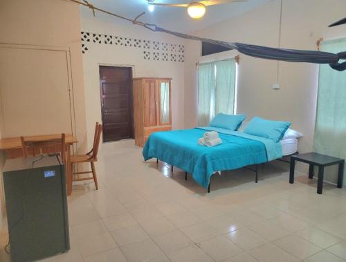 a bedroom with a blue bed and a table at Arnold's Guest House in San Ignacio