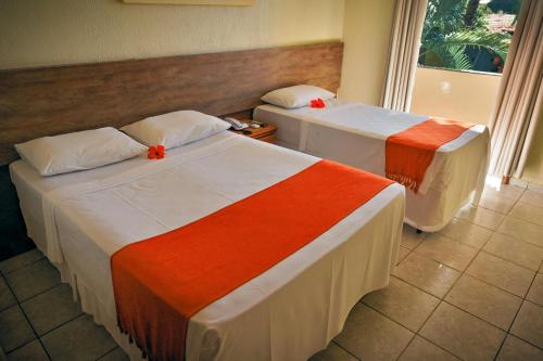 two beds in a hotel room with red bows on them at Ayla Praia Hotel Centro Porto Segur in Porto Seguro