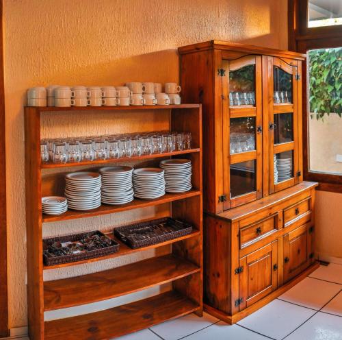 a wooden cabinet with plates and dishes in it at Ayla Praia Hotel Centro Porto Segur in Porto Seguro