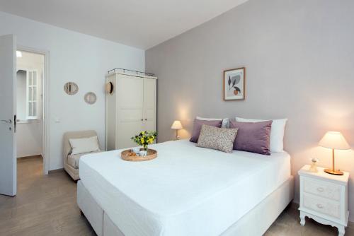 a bedroom with a large white bed with purple pillows at NiSea Apartments in Ipsos
