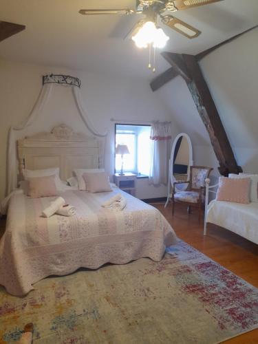 a bedroom with a large white bed and a chair at La Maison du Prince de Condé in Charroux-dʼAllier