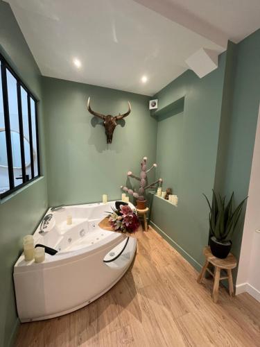 La salle de bains est pourvue d'une baignoire avec tête de bœuf sur le mur. dans l'établissement Suite avec Jacuzzi, 15 min de Disneyland Paris - Le Nid d'Eliyah, à Nanteuil-lès-Meaux