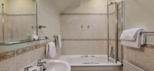 een badkamer met een bad, een wastafel en een douche bij Enniskeen Country House Hotel in Newcastle