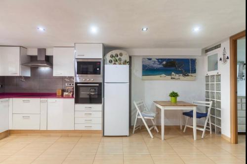 a kitchen with a white refrigerator and a table at Villa del Mar in Puebla de Farnals