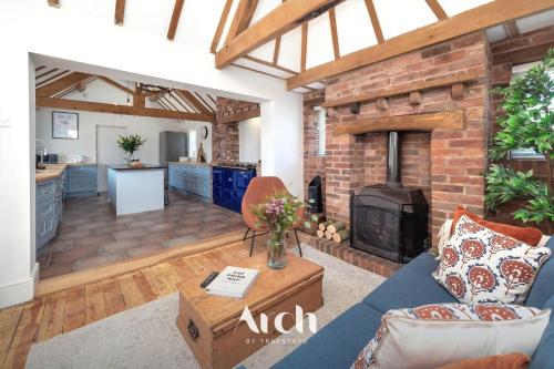 a living room with a blue couch and a brick fireplace at NEW - Country House, Staffordshire in Abbots Bromley