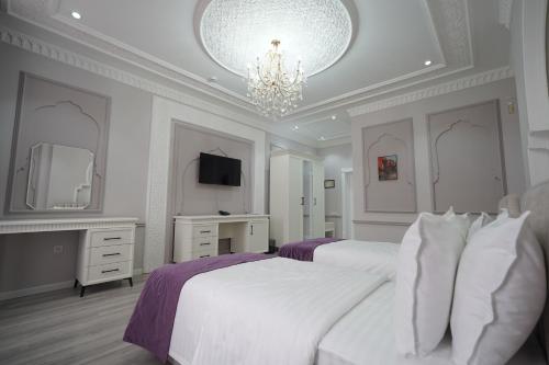 a white bedroom with two beds and a chandelier at Hotel Dali Samarkand in Samarkand