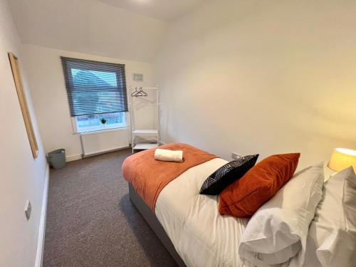 um quarto com uma cama com almofadas laranja e uma janela em Spacious 5-bed house in Coventry by Seeka Stay, Ideal for business, Sleeps 7! em Exhall