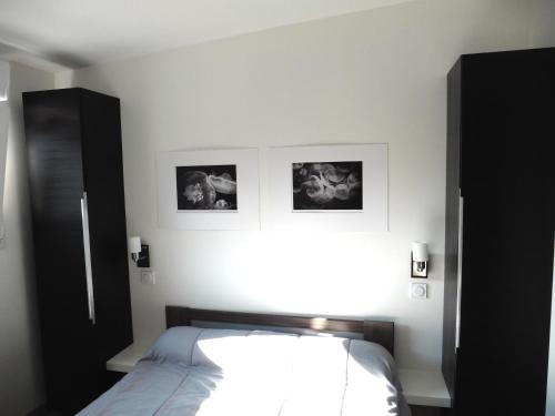 een slaapkamer met een bed en twee foto's aan de muur bij Cottages de la ville Daniou in Langrolay