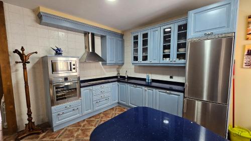 cocina con armarios azules y nevera de acero inoxidable en la casa del abuelo, en Sebúlcor