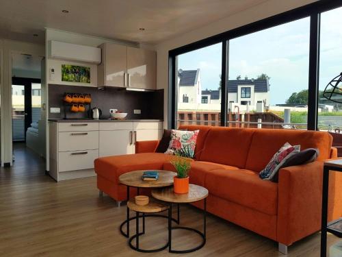 a living room with an orange couch and a kitchen at Hausboot Marama - LP10 in Peenemünde