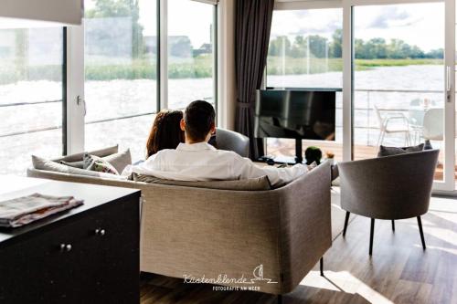 a man and a woman sitting on a couch watching a tv at Hausboot KranichNest in Ribnitz-Damgarten