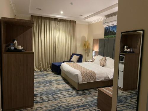 Habitación de hotel con cama y silla en سكون سويت للشقق الفندقية en Hail