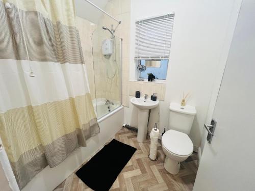 a bathroom with a toilet and a sink and a shower at Spacious 5 Bed House in Exhall