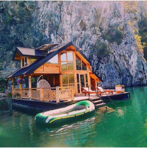 ein Haus auf dem Wasser mit einem Boot im Wasser in der Unterkunft Splav Horizont in Gaočići