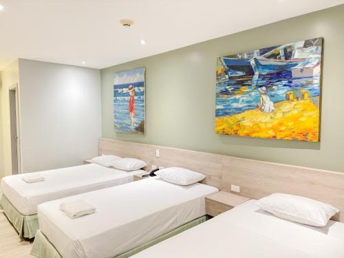 um quarto com três camas e um quadro na parede em GH Sander Hotel em Guayaquil