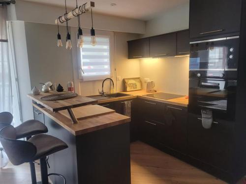 une cuisine avec des armoires noires et un comptoir en bois dans l'établissement Magnifique T2 meublé au pied du port, à Capbreton