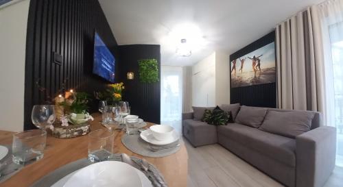 ein Wohnzimmer mit einem Tisch und einem Sofa in der Unterkunft Apartament Koszałka in Łeba