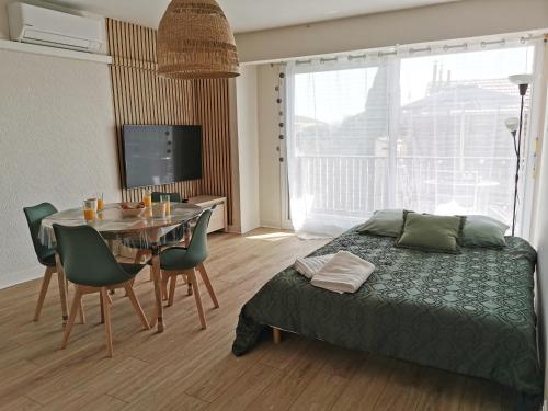 une chambre avec un lit et une table avec des chaises dans l'établissement Appart'Cosy - clim - terrasse - ascenseur, à Cavaillon