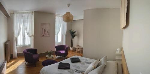 a living room with a bed and purple chairs at Couette et Tartine in Chalon-sur-Saône