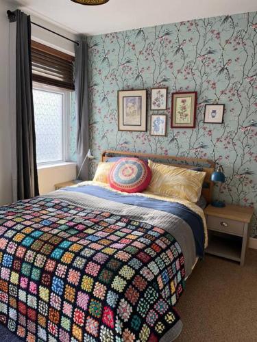 a bedroom with a bed with a colorful quilt at Just the Splott! Sleeps 6, 8 mins to Stadium. in Cardiff
